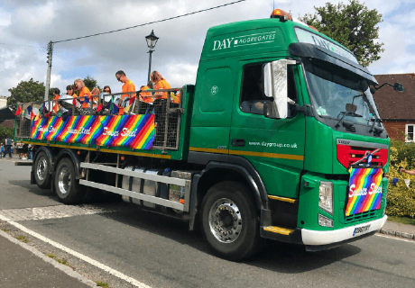 Day Aggregates lorry driving along with a group of people in the flatbed on the back