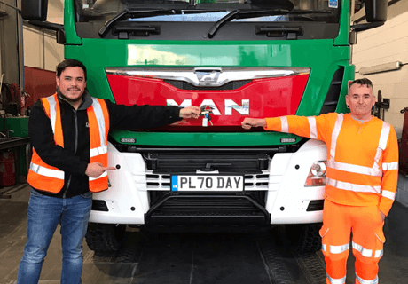 two workers in PPE standing in front of a green day aggregates lorry