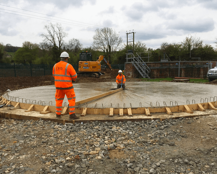 Two men in PPE working on a water filtration tank