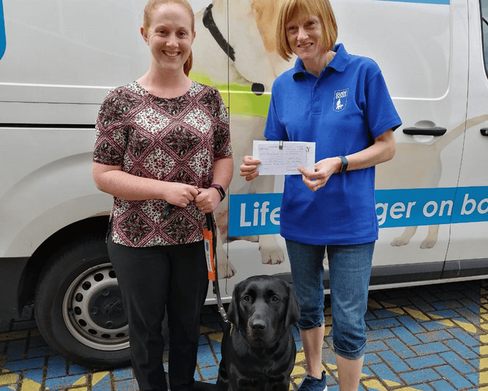 two ladies with a service dog and a certificate