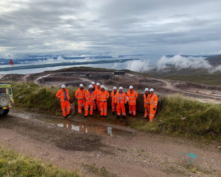 Group of workers in PPE with a quarry in the background