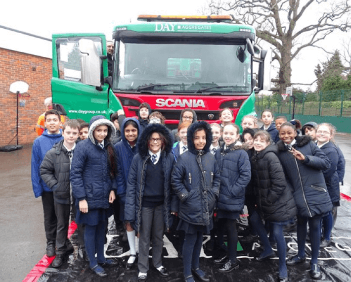 Group of kid standing in front of a Day Aggregates lorry