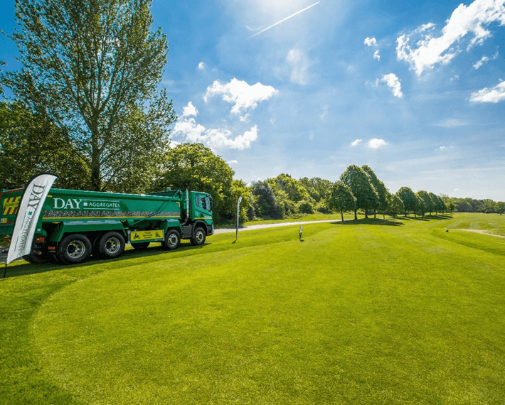 sunny golf course with a green day aggregates lorry