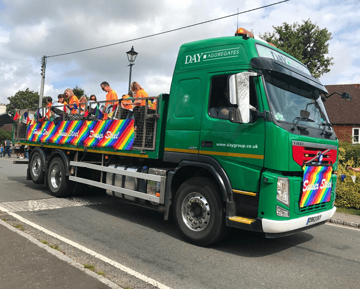 Day Aggregates lorry driving along with a group of people in the flatbed on the back