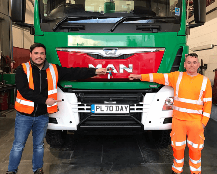 two workers in PPE standing in front of a green day aggregates lorry