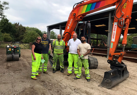 Workers standing in front of a red excavator