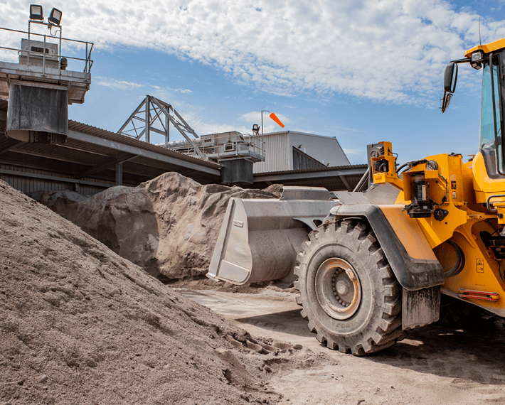 Yellow shovel machine shovelling a pile of IBA