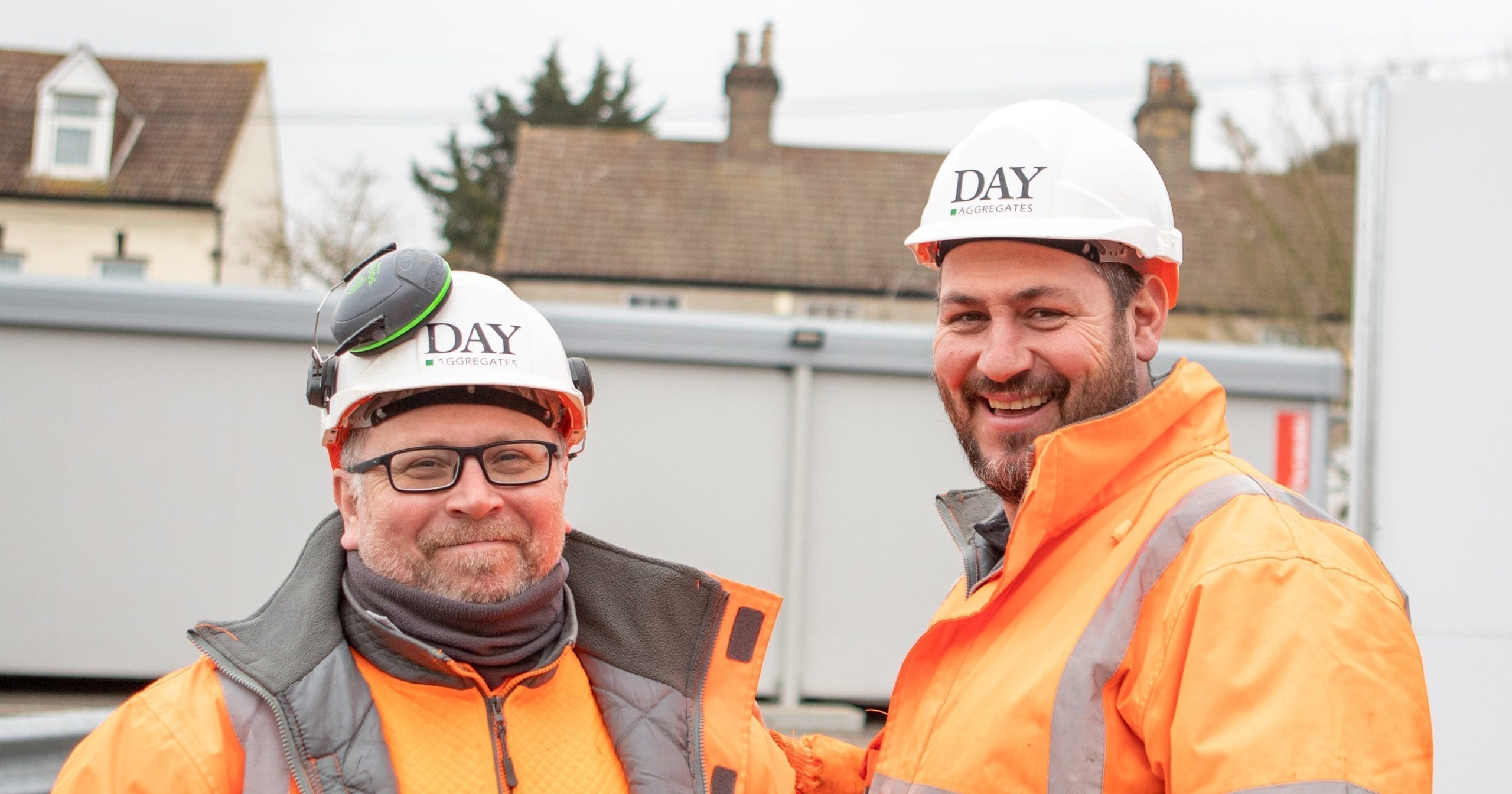 Two workers in PPE smiling at the camera