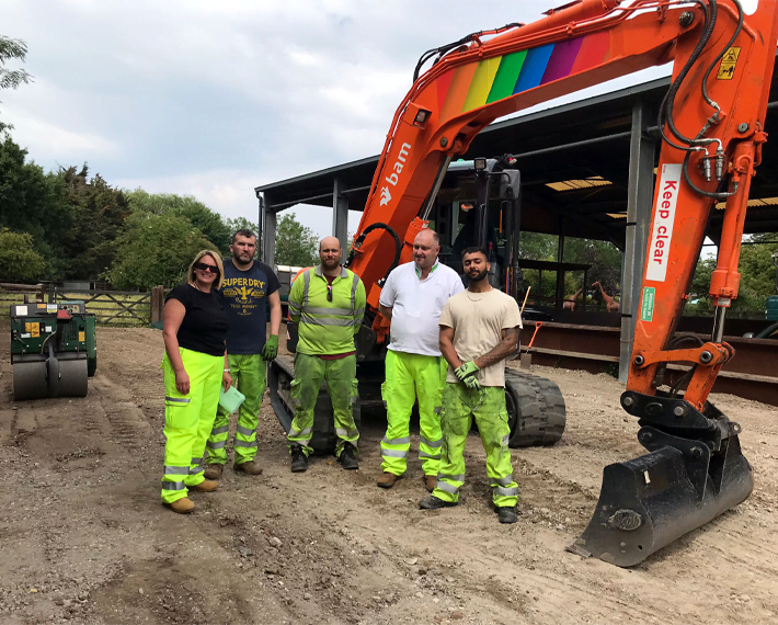 Workers standing in front of a red excavator
