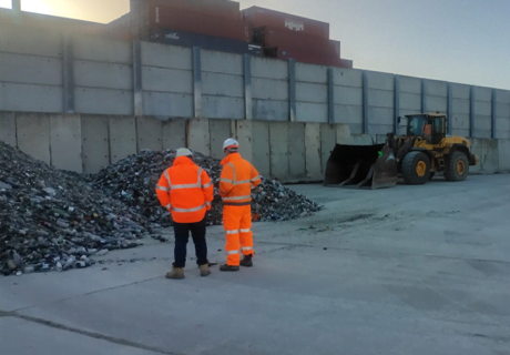 two workers in PPE standing over a pile of recycled glass